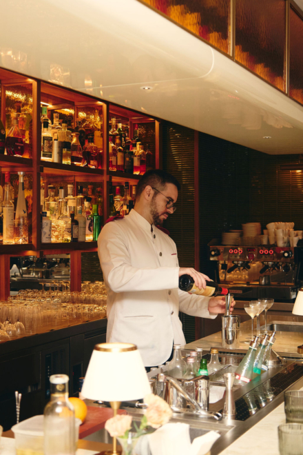 Bartender preparando un cóctel en la barra de Finorri con botellero iluminado al fondo