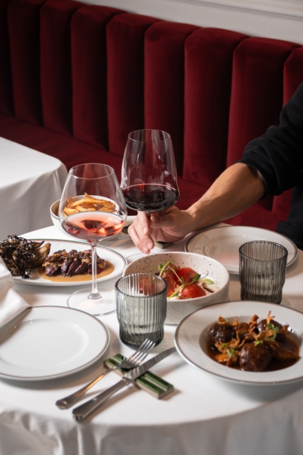 Copas de vino tinto y rosado junto a platos de cocina catalana en el banco de terciopelo rojo