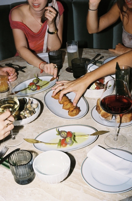 Grupo de amigas compartiendo croquetas, ostras y otros platos con vino tinto